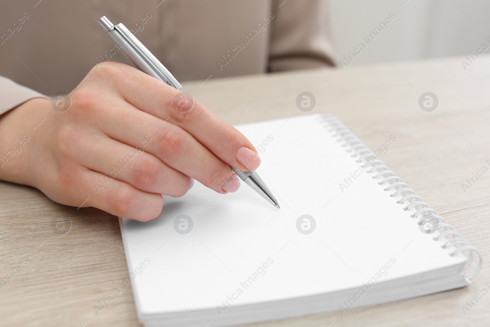 Photo of Woman writing in notebook at wooden table, closeup