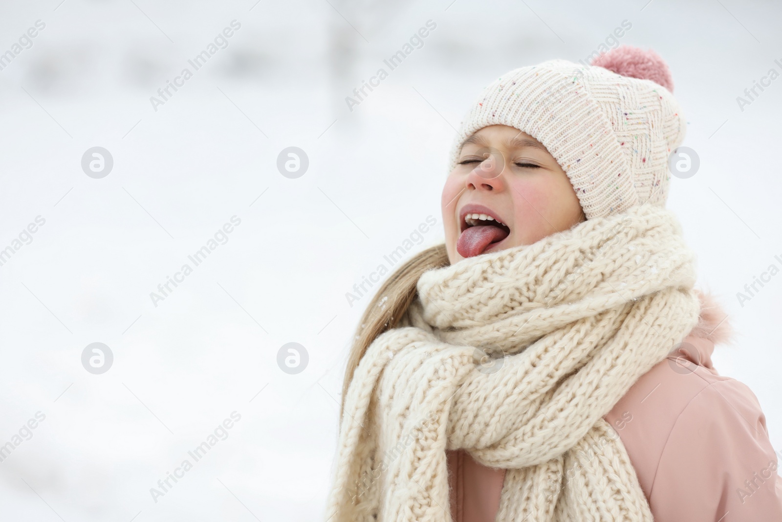 Photo of Cute little girl having fun in snowy park on winter day, space for text