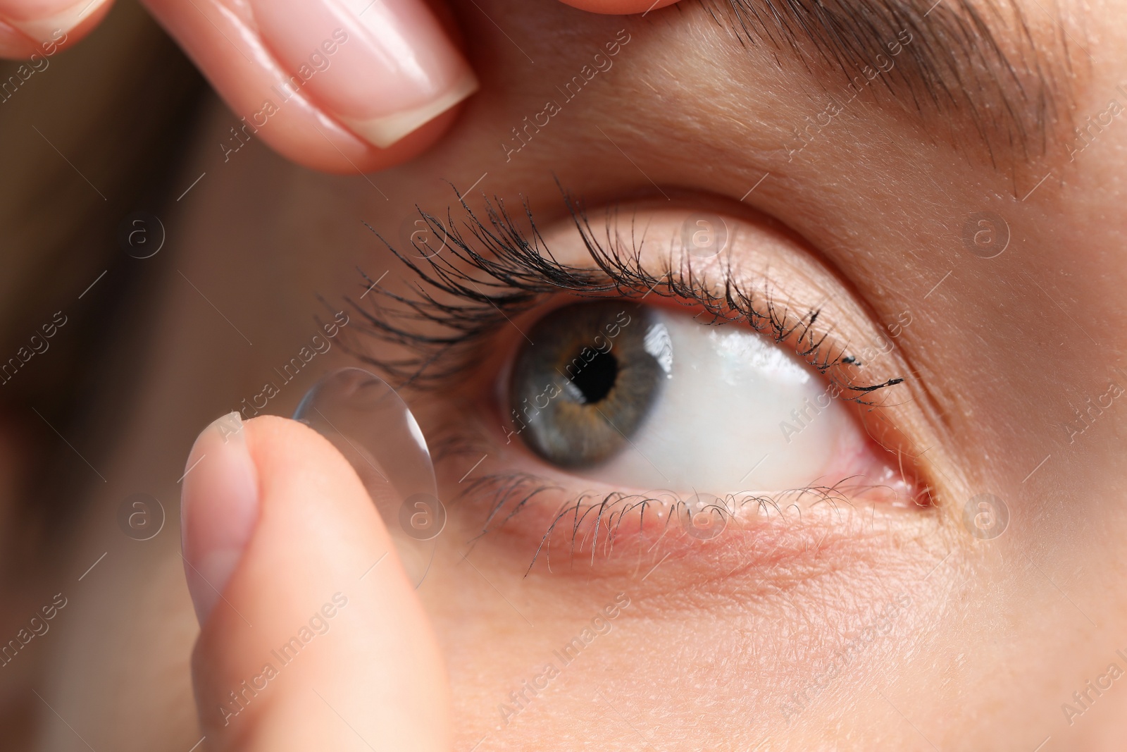 Photo of Woman putting in contact lens, closeup view