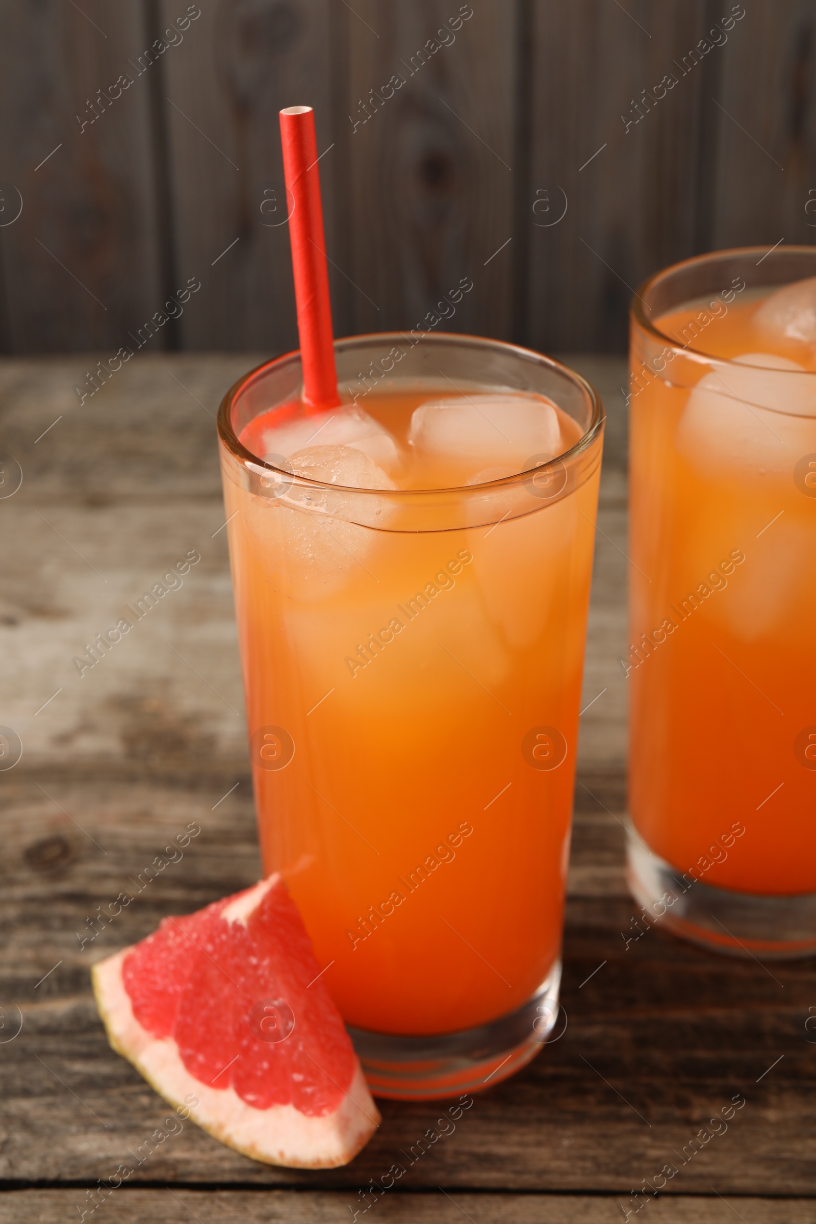 Photo of Tasty freshly made grapefruit juice and fruit on wooden table