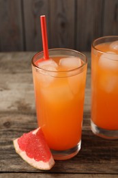Photo of Tasty freshly made grapefruit juice and fruit on wooden table