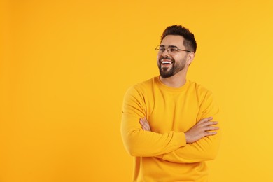 Handsome man wearing glasses on orange background, space for text