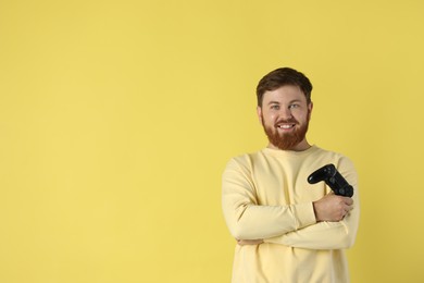 Photo of Smiling man with game controller on pale yellow background. Space for text