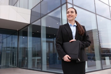 Photo of Female real estate agent with leather portfolio outdoors