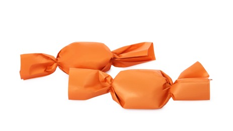 Photo of Delicious candies in orange wrappers on white background