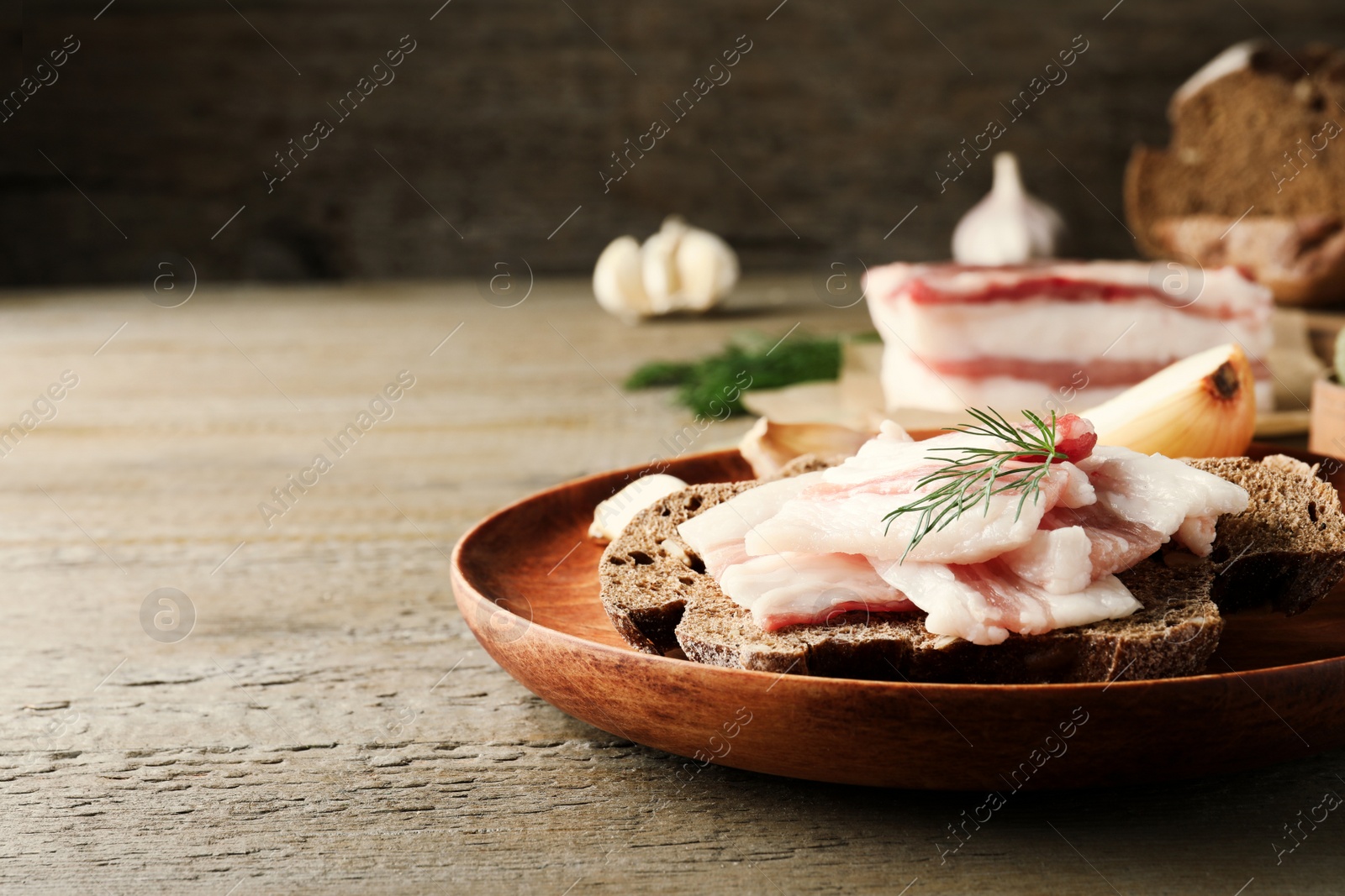 Photo of Tasty salt pork with rye bread and dill on wooden table, space for text