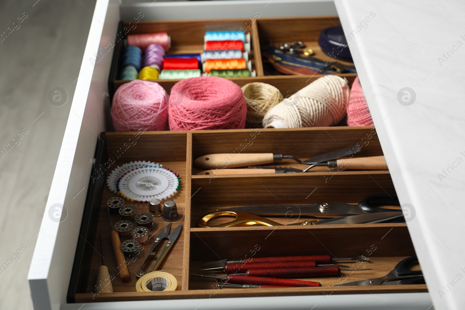 Photo of Sewing accessories in open desk drawer indoors