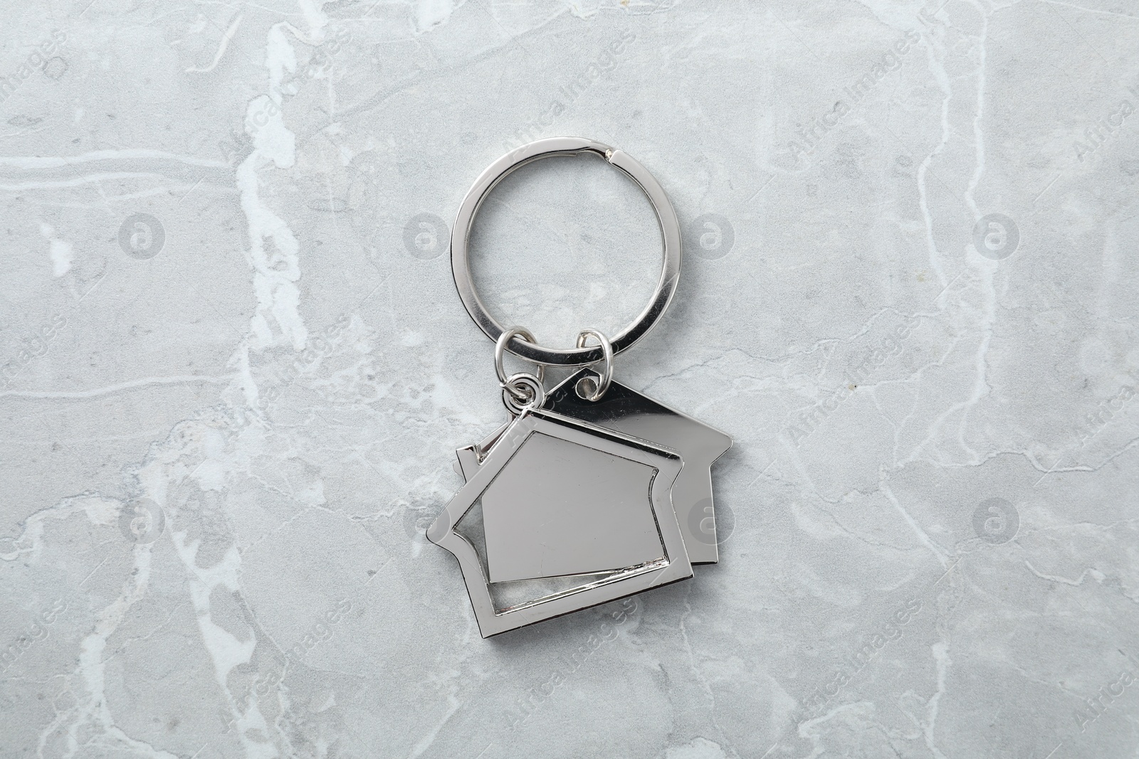 Photo of Metal keychain in shape of houses on grey marble table, top view