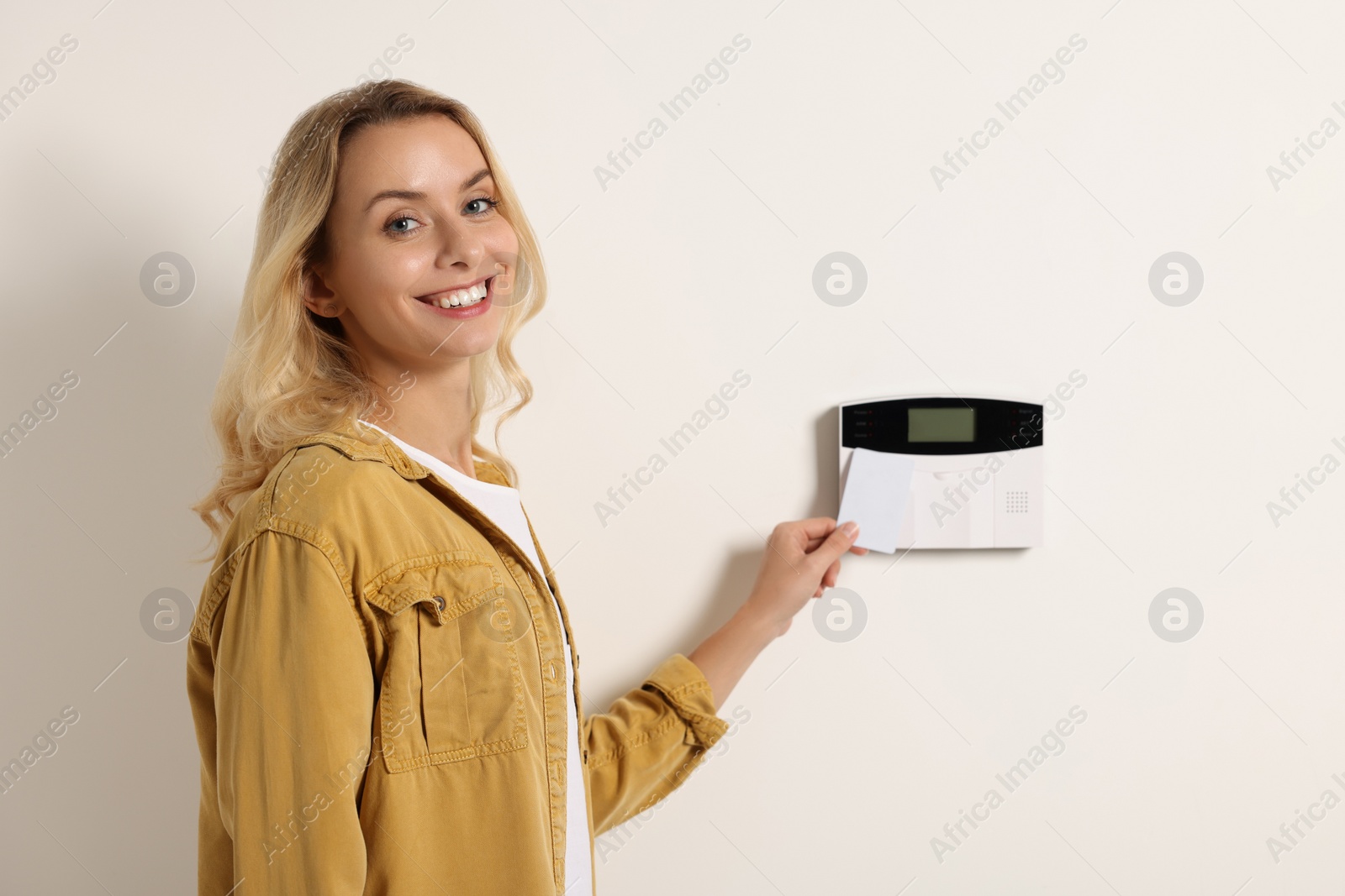 Photo of Home security system. Woman using key card indoors