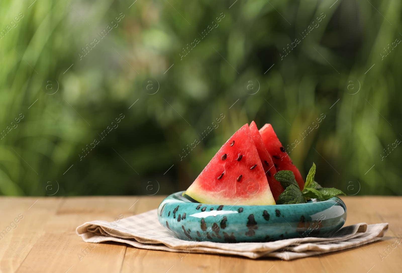 Photo of Slices of delicious ripe watermelon on wooden table outdoors, space for text