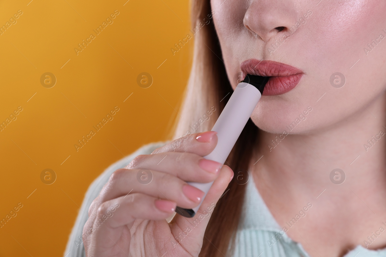 Photo of Young woman using electronic cigarette on orange background, closeup. Space for text