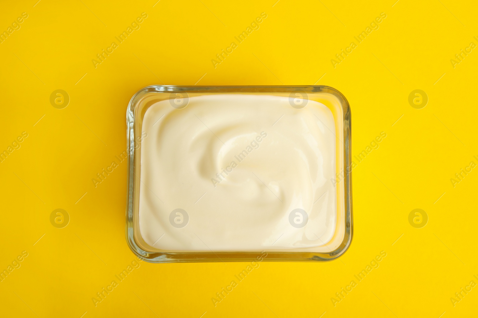 Photo of Tasty organic yogurt on yellow background, top view