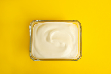 Photo of Tasty organic yogurt on yellow background, top view