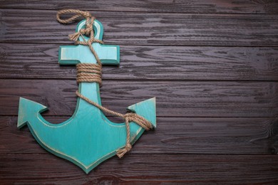 Anchor with hemp rope on dark wooden table, top view. Space for text