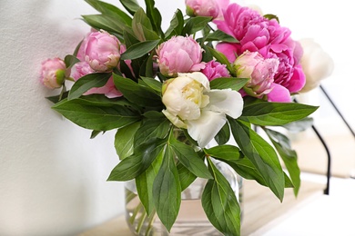 Photo of Shelf with vase of beautiful peonies on white wall