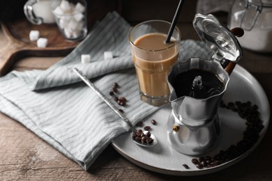 Photo of Brewed coffee in moka pot, glass of drink and beans on wooden table, space for text