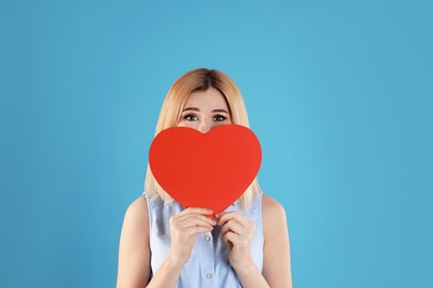 Beautiful woman with paper heart on color background