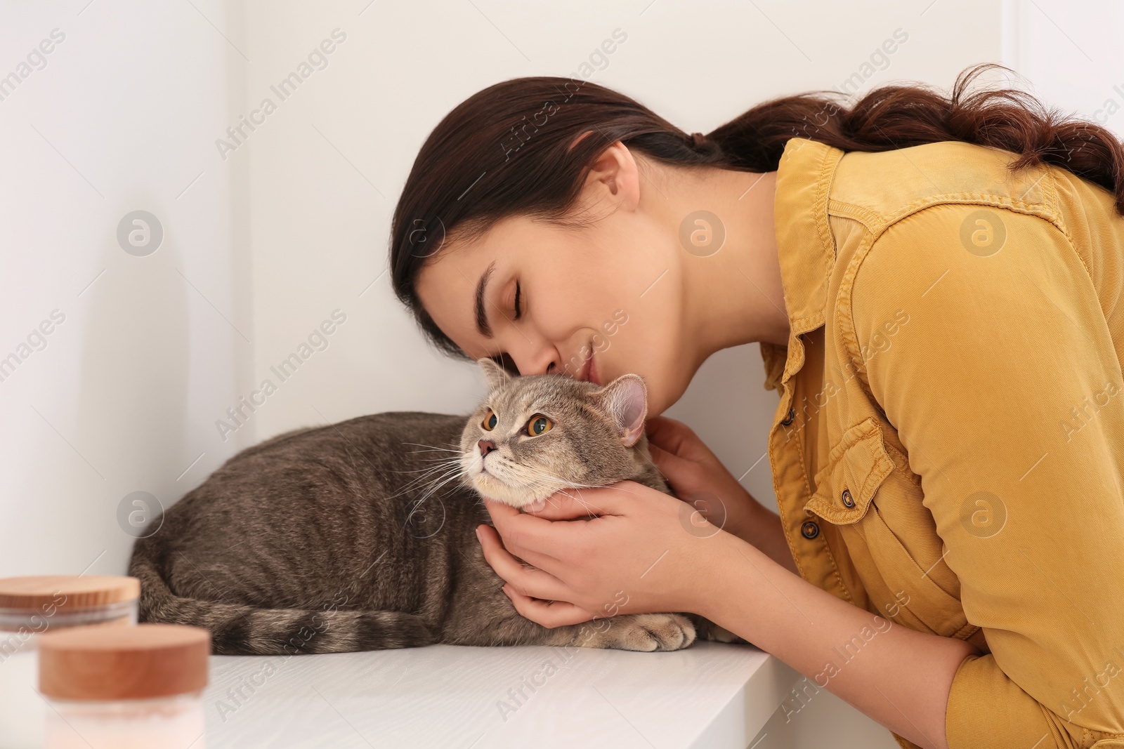 Photo of Young woman kissing her adorable cat at home