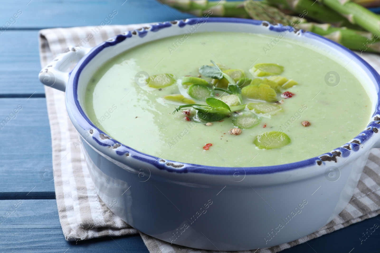 Photo of Delicious asparagus soup on blue wooden table, closeup