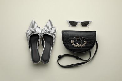 Photo of Stylish woman's bag, shoes, earrings and sunglasses on light background, flat lay
