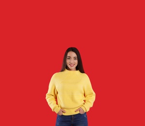 Photo of Beautiful young woman wearing yellow warm sweater on red background