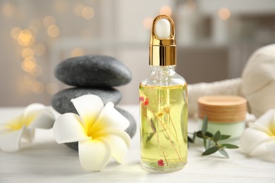 Photo of Beautiful spa composition with essential oil and plumeria flowers on white table against blurred lights
