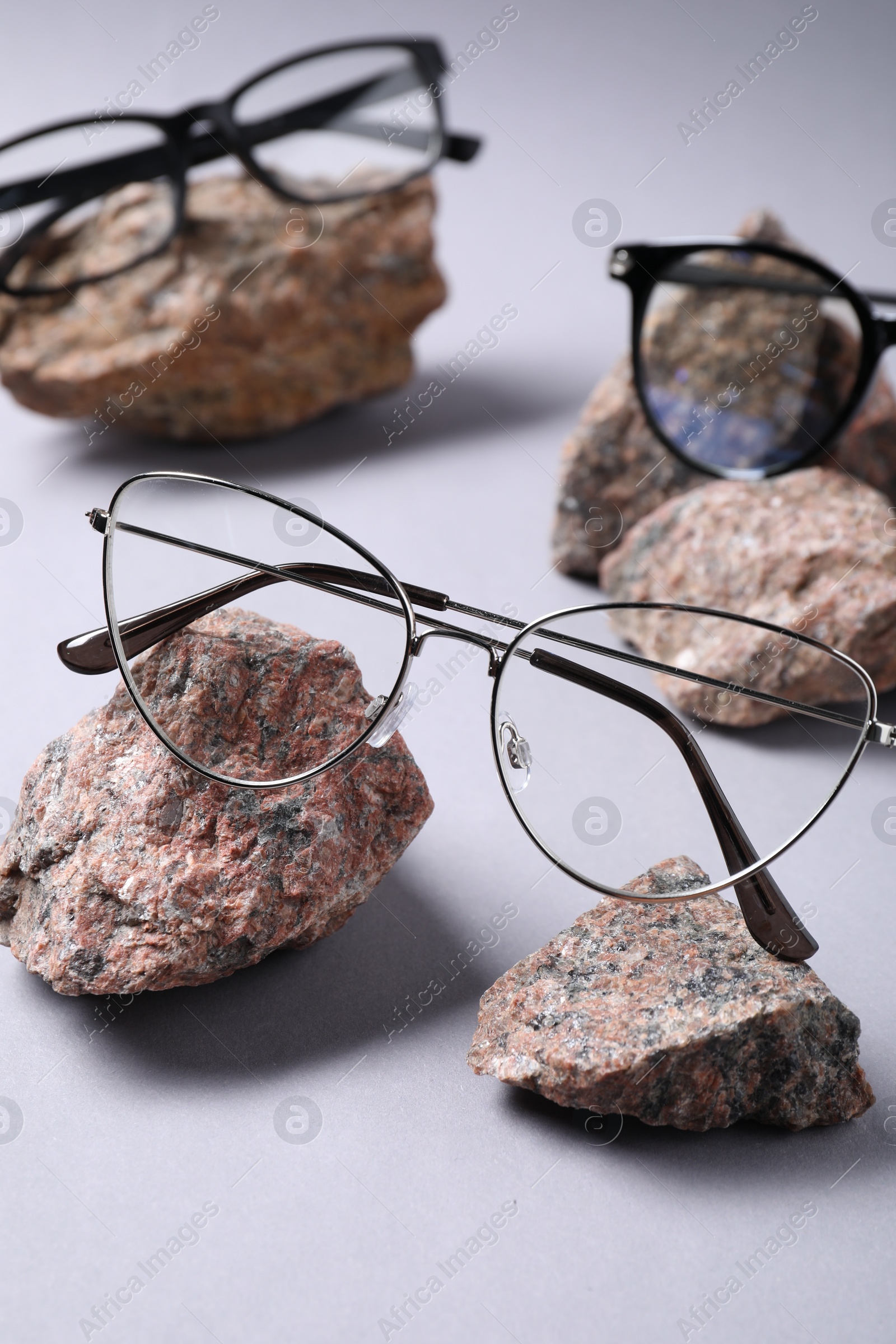 Photo of Different stylish glasses on stones against white background, closeup