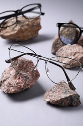 Photo of Different stylish glasses on stones against white background, closeup
