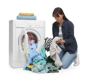 Photo of Unhappy woman with dirty clothes near washing machine on white background