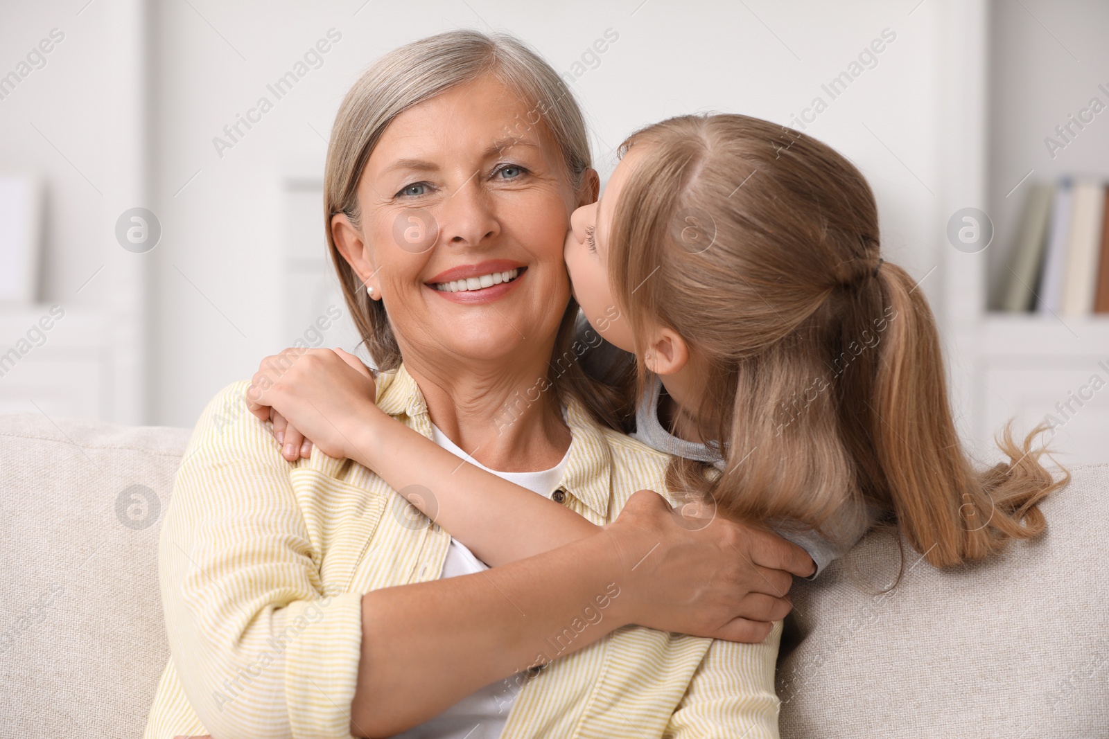 Photo of Happy granddaughter kissing her grandmother at home