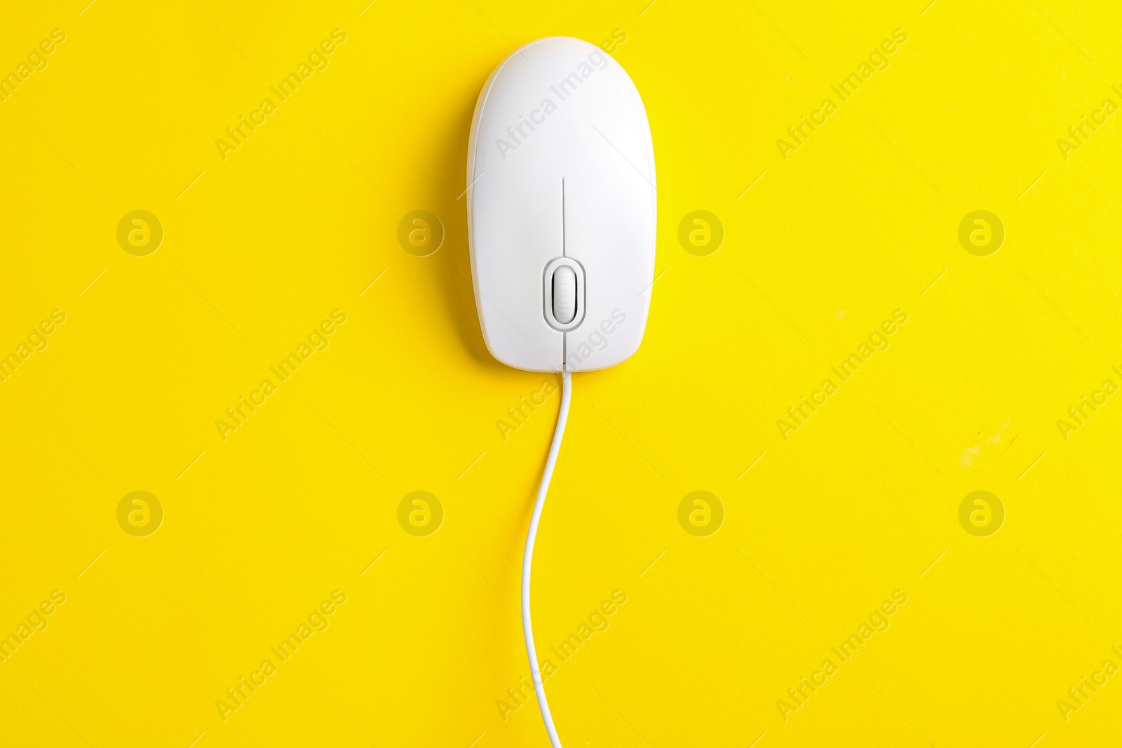 Photo of Modern wired optical mouse on yellow background, top view