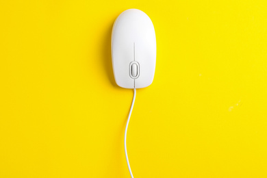 Photo of Modern wired optical mouse on yellow background, top view