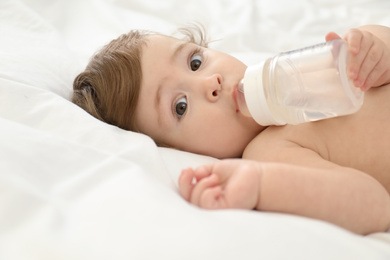 Photo of Cute little baby with bottle on bed