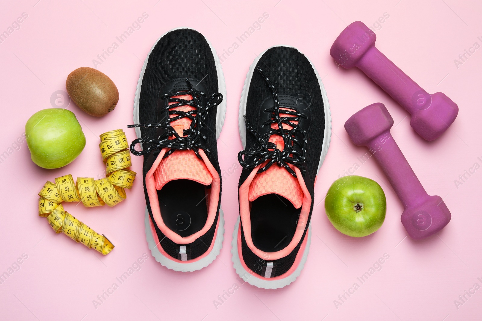 Photo of Weight loss concept. Flat lay composition with sneakers, fitness items and fruits on pink background