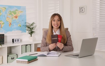 Photo of Happy manager holding passports at desk in travel agency