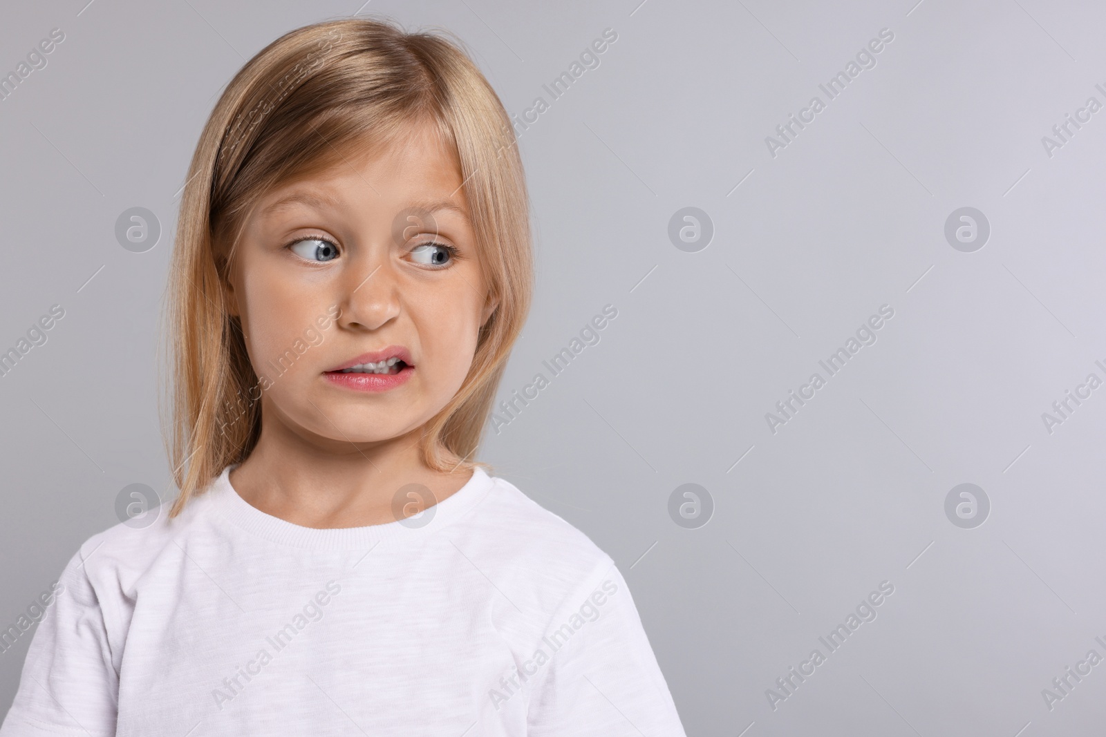 Photo of Embarrassed little girl on grey background. Space for text