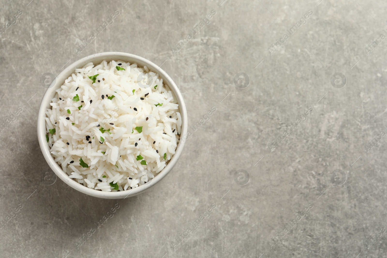 Photo of Bowl of tasty cooked rice on grey background, top view. Space for text