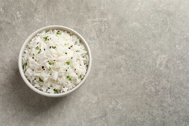 Bowl of tasty cooked rice on grey background, top view. Space for text