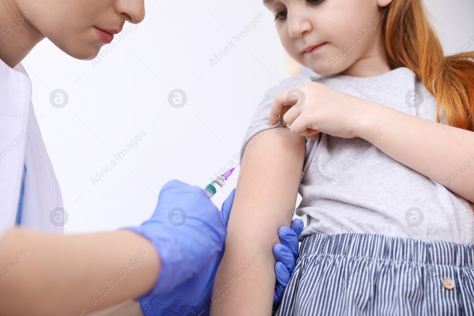 Photo of Little girl receiving chickenpox vaccination on white background, closeup. Varicella virus prevention