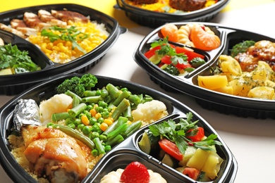 Photo of Lunchboxes with different meals on white table, closeup. Healthy food delivery