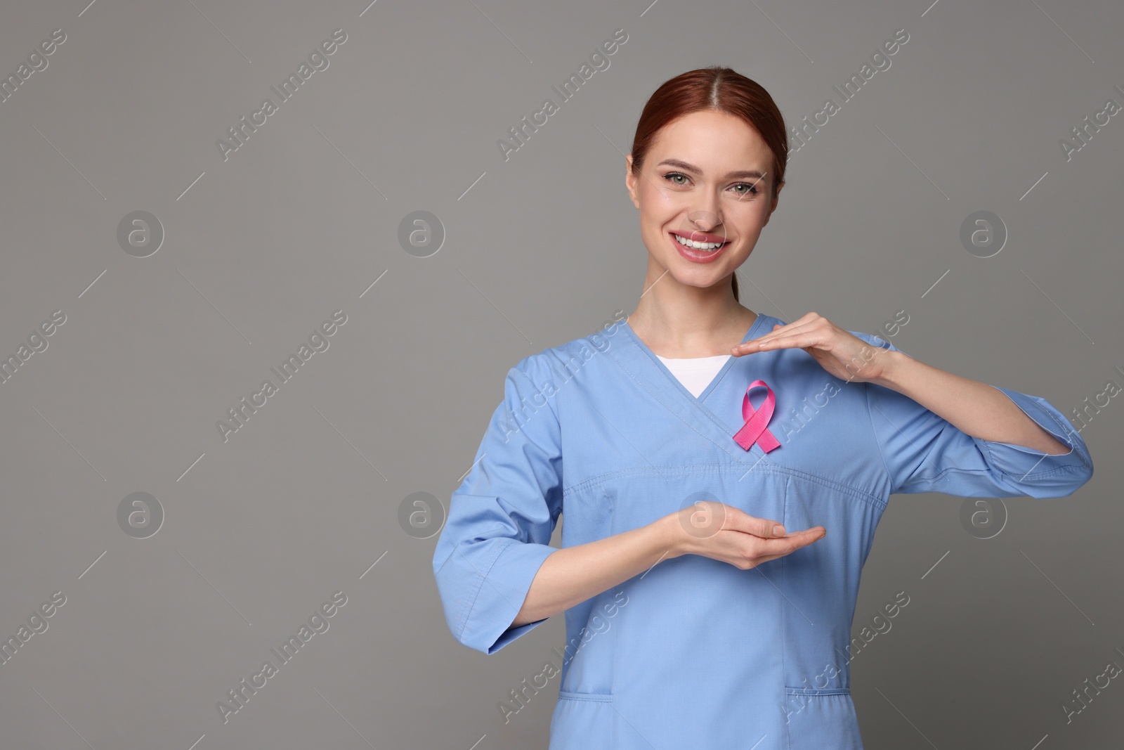 Photo of Mammologist with pink ribbon on gray background, space for text. Breast cancer awareness
