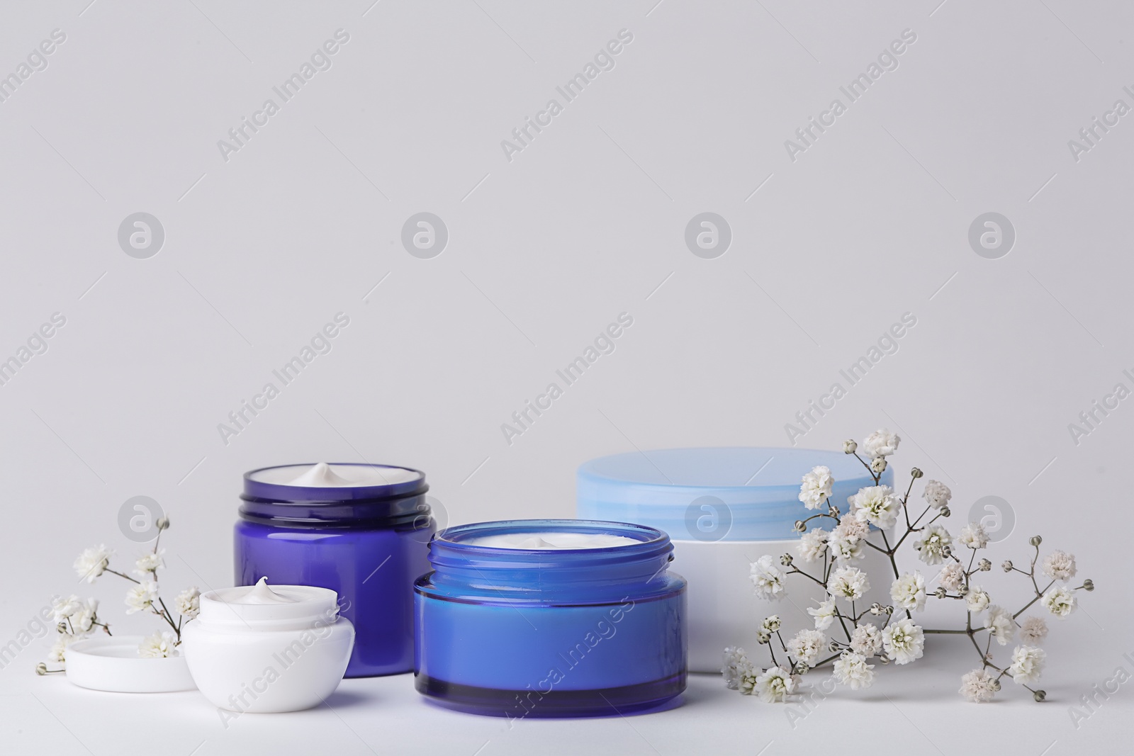 Photo of Jars of body cream on light background