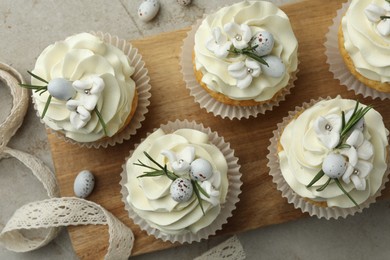 Tasty Easter cupcakes with vanilla cream and ribbon on gray table, flat lay