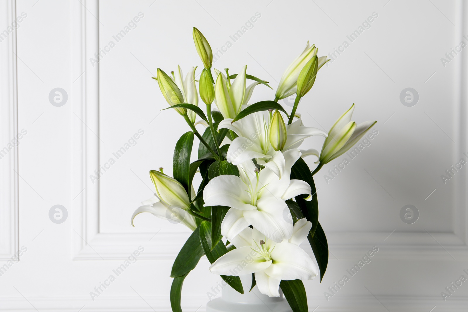 Photo of Beautiful bouquet of lily flowers near white wall