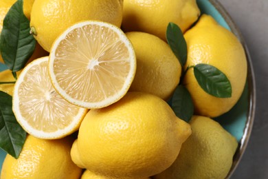 Photo of Fresh lemons and green leaves on grey table, top view