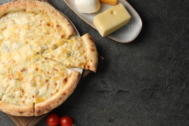 Photo of Delicious cheese pizza, tomatoes and different kinds of cheese on dark grey table, flat lay. Space for text