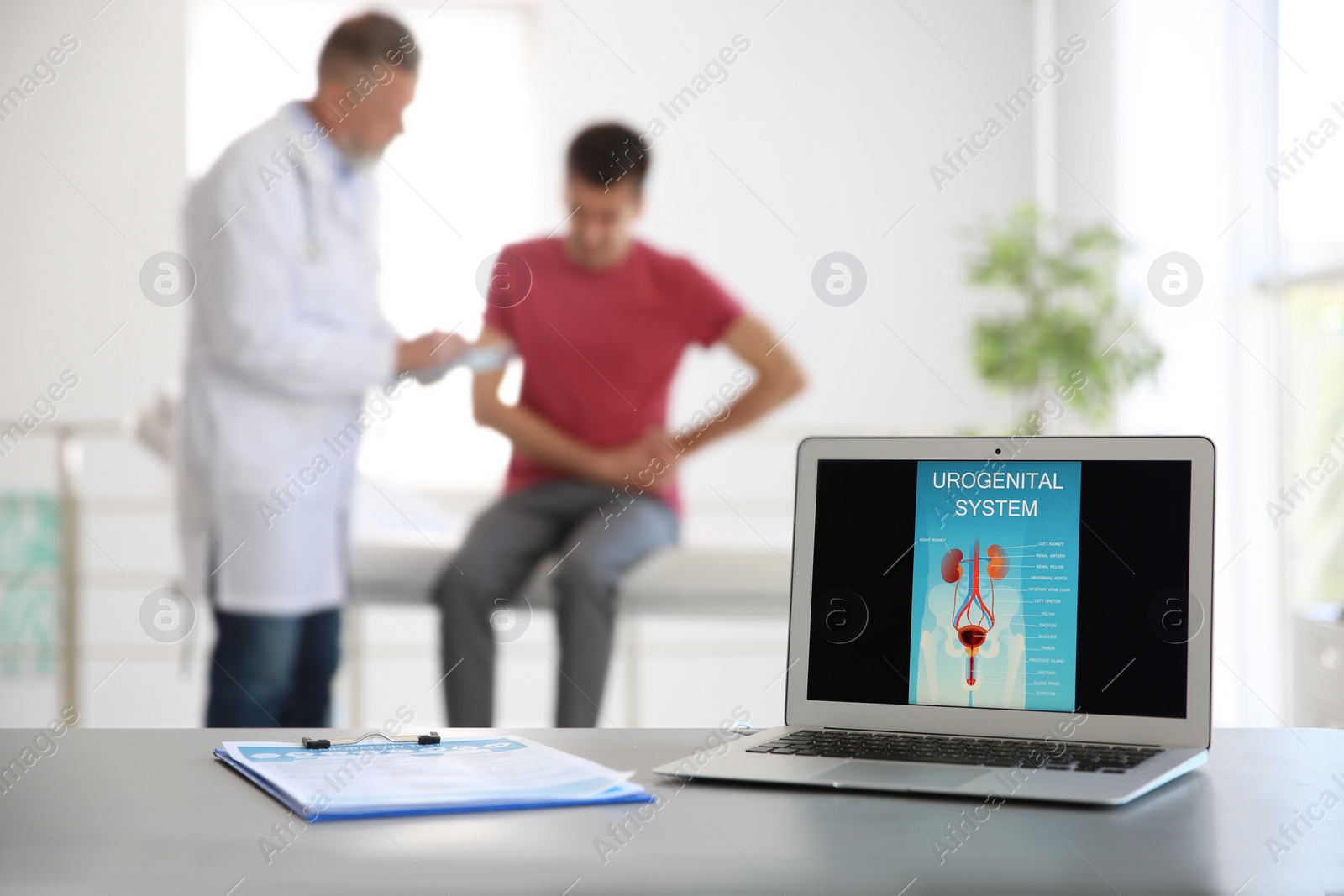 Photo of Laptop with picture of urogenital system and blurred people on background