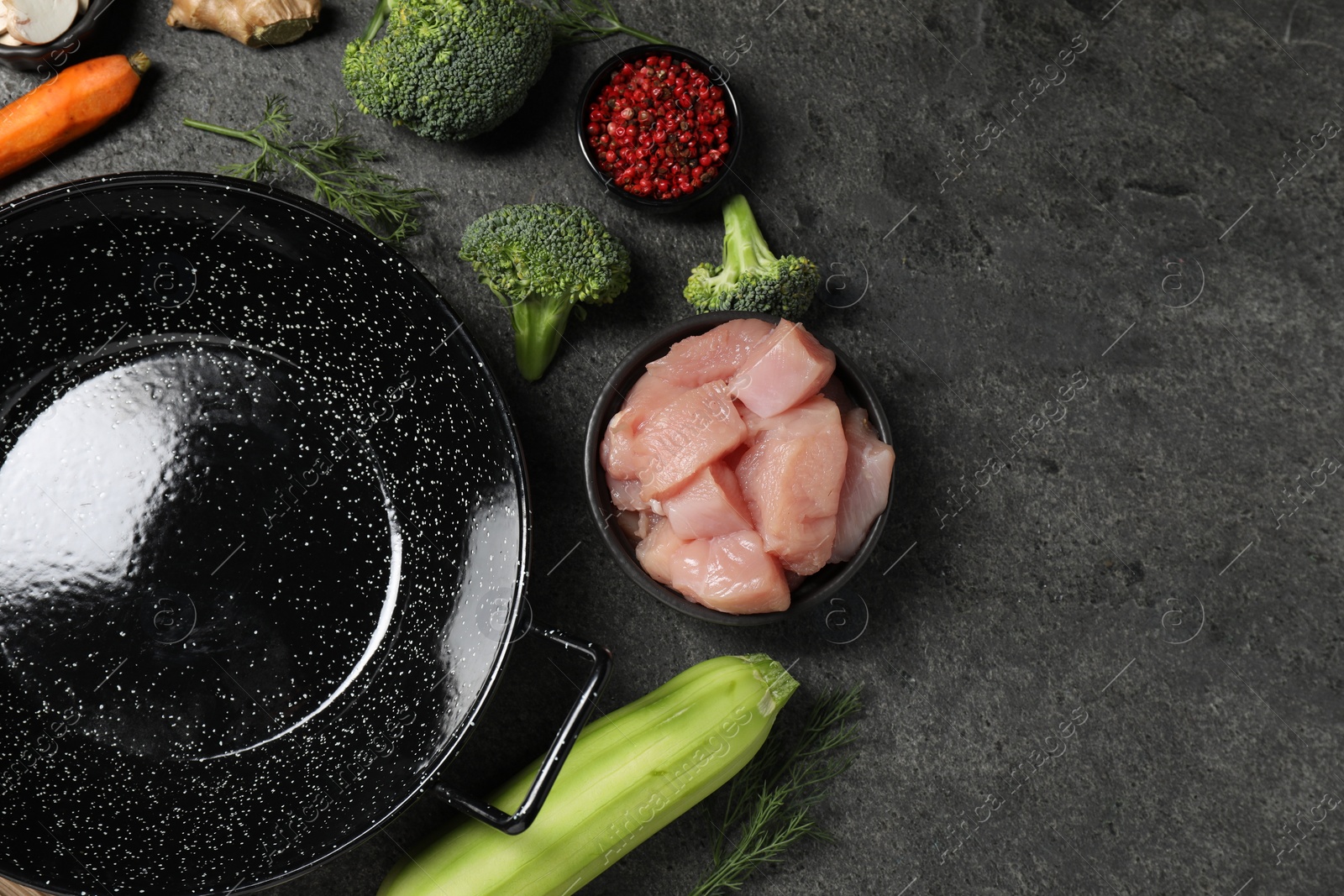 Photo of Empty iron wok and raw ingredients on grey table, flat lay. Space for text