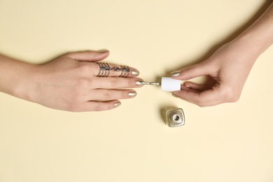 Photo of Woman applying nail polish on color background, top view