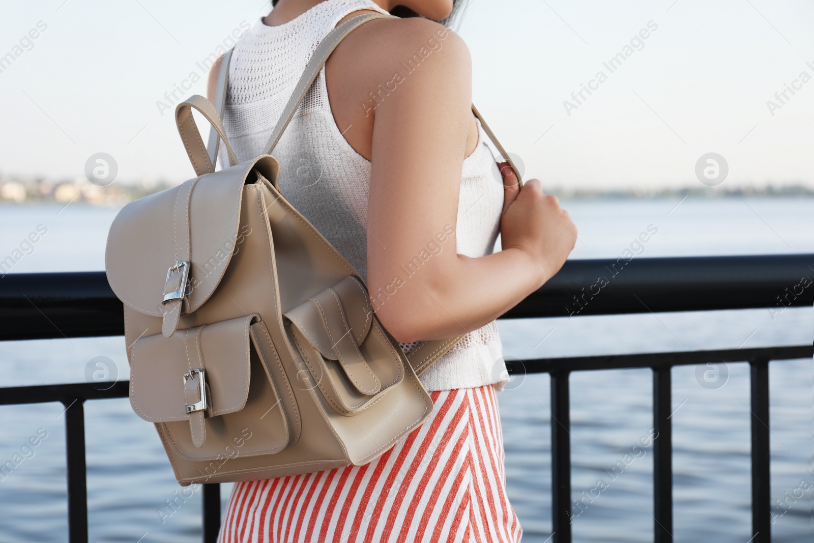 Photo of Young woman with stylish backpack near river, closeup